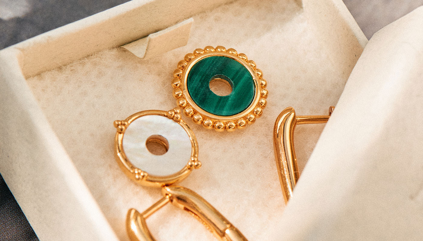 Gold charms featuring malachite and mother pearl with gold hoops in jewellery box